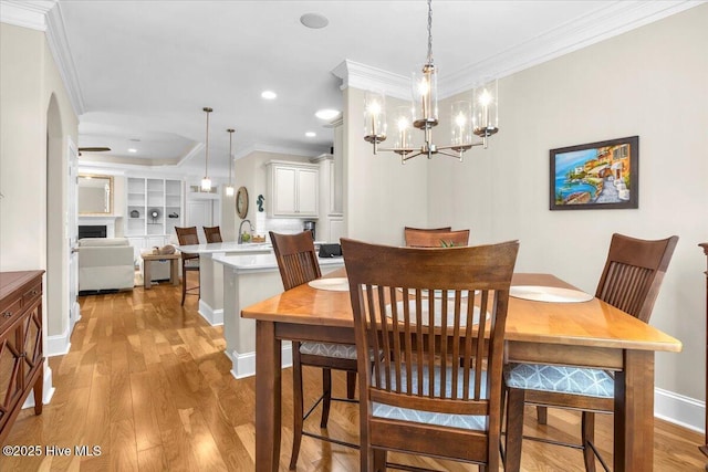 1013 Dowling Ct, Leland, NC 28451 - dining room with ornamental molding, light wood-type flooring, a fireplace, arched walkways, and baseboards