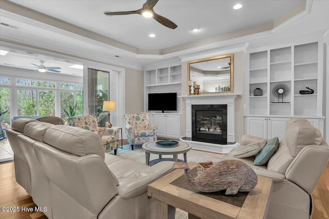1013 Dowling Ct, Leland, NC 28451 - living area with a ceiling fan, a glass covered fireplace, ornamental molding, light wood-style floors, and built in features