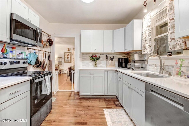 1605 E Holly St, Goldsboro, NC 27530 - kitchen featuring appliances with stainless steel finishes, a sink, light wood-style floors, light countertops, and decorative backsplash