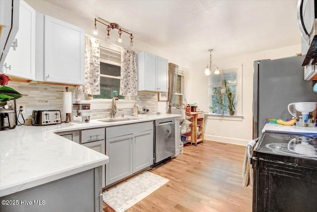 1605 E Holly St, Goldsboro, NC 27530 - kitchen with stainless steel appliances, backsplash, a chandelier, light wood finished floors, and hanging light fixtures