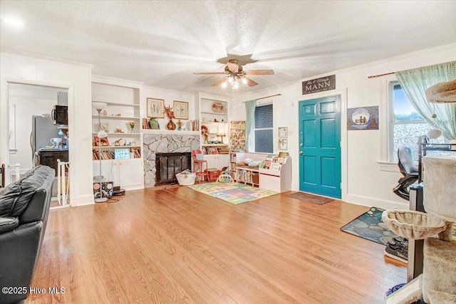 1605 E Holly St, Goldsboro, NC 27530 - living area with wood finished floors, a textured ceiling, ceiling fan, a stone fireplace, and ornamental molding