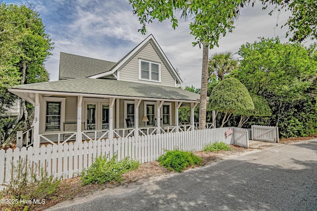 659 Wash Woods Way, Bald Head Island, NC 28461 - view of front of home with a porch, a shingled roof, a fenced front yard, and a gate