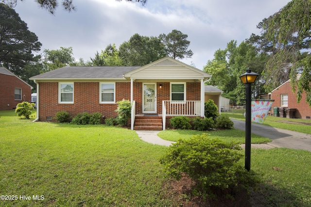 view of front of home with brick siding, a front yard, and covered porch