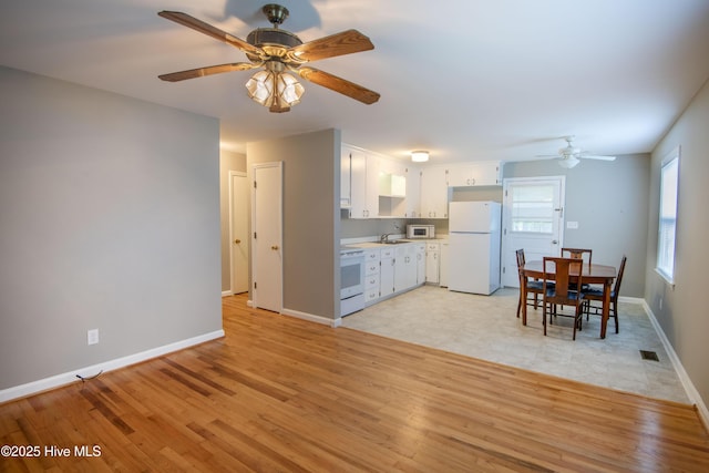 kitchen featuring white appliances, ceiling fan, light countertops, and light wood-type flooring