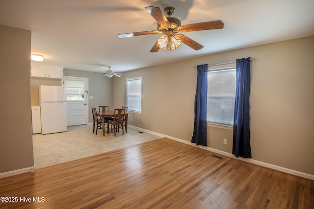 dining area featuring light wood-style floors, baseboards, and a ceiling fan