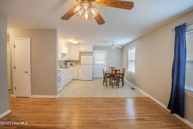 dining area with a ceiling fan, light wood finished floors, and baseboards
