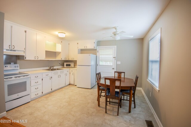 kitchen featuring white appliances, under cabinet range hood, a sink, a ceiling fan, and white cabinetry
