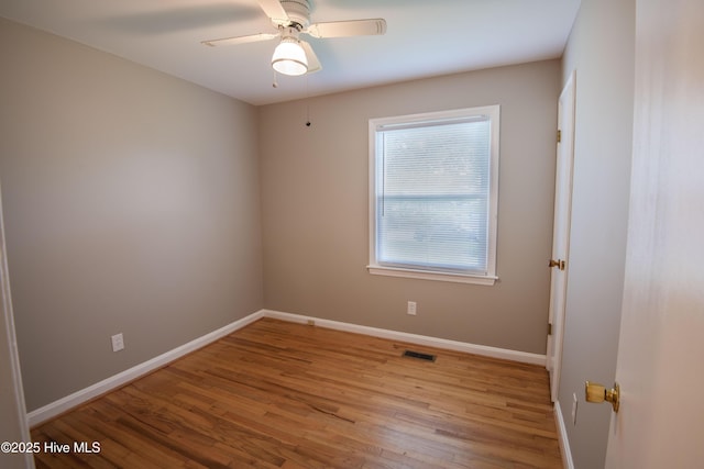 empty room featuring wood finished floors, baseboards, and a ceiling fan