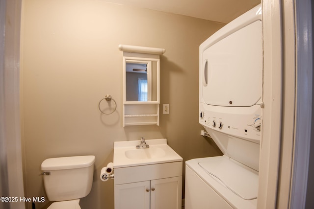 half bath with estacked washer and dryer, toilet, and vanity