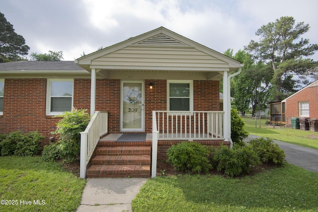 view of front facade featuring a porch, brick siding, and a front yard