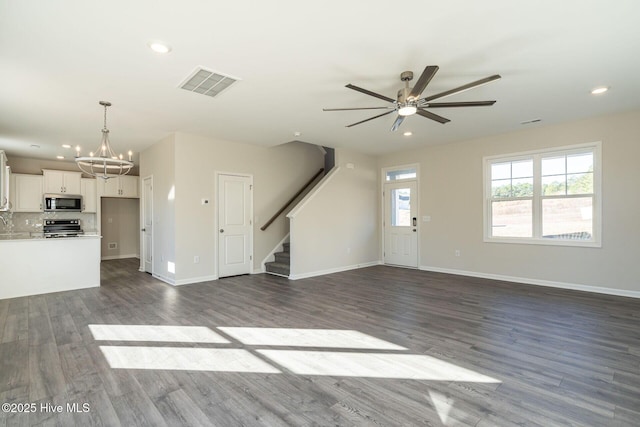 unfurnished living room featuring stairs, a chandelier, dark wood finished floors, recessed lighting, and ceiling fan