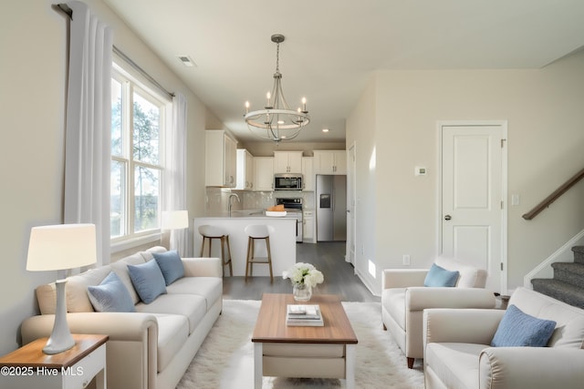 living area with a chandelier, wood finished floors, healthy amount of natural light, stairway, and recessed lighting