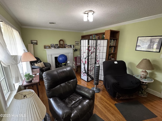 living room with a textured ceiling, wood finished floors, ornamental molding, a brick fireplace, and baseboards