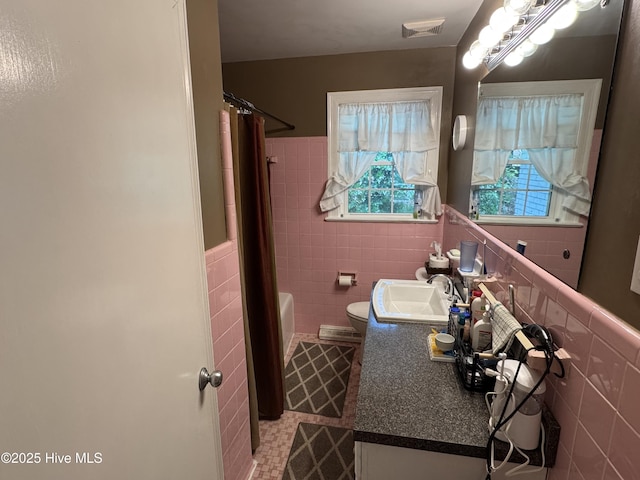bathroom with tile walls, tile patterned floors, vanity, a wainscoted wall, and toilet