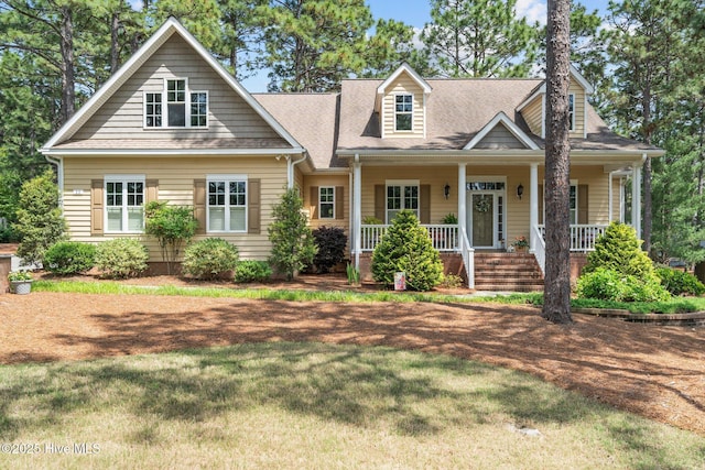 view of front of property with a front lawn, covered porch, and a shingled roof