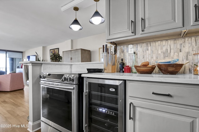 kitchen featuring beverage cooler, light countertops, a peninsula, light wood-style flooring, and hanging light fixtures