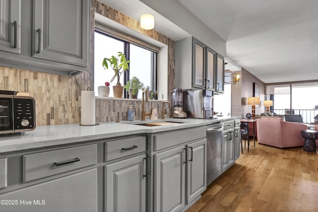 kitchen with dishwasher, a sink, gray cabinets, and tasteful backsplash