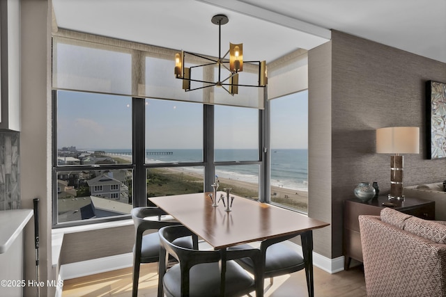 dining space with a chandelier, wood finished floors, a water view, and baseboards