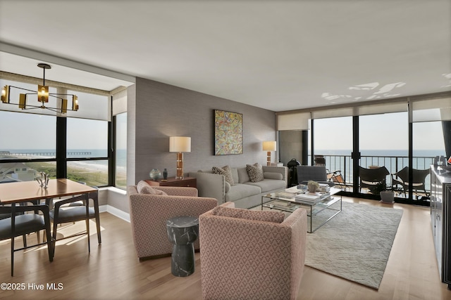 living area featuring a wall of windows, healthy amount of natural light, wood finished floors, and a water view