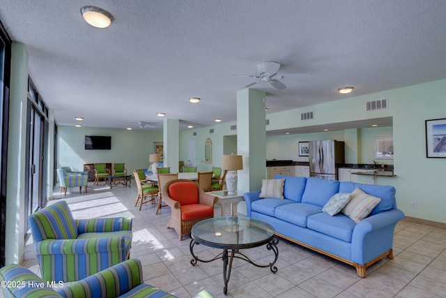 living room featuring a ceiling fan, light tile patterned floors, and a textured ceiling