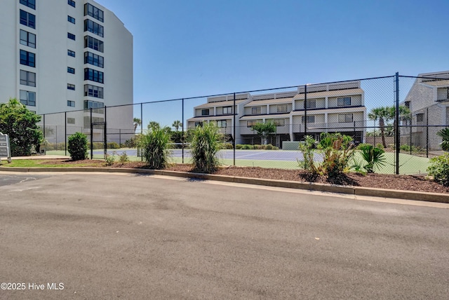 view of building exterior with fence and uncovered parking