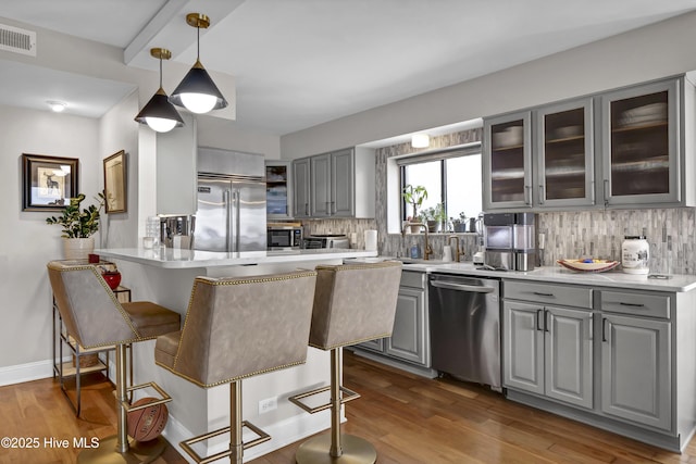 kitchen with gray cabinets, appliances with stainless steel finishes, a kitchen breakfast bar, and a peninsula