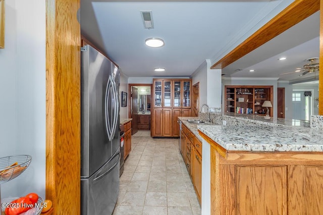4512 Rivershore Dr, New Bern, NC 28560 - kitchen featuring freestanding refrigerator, ornamental molding, a sink, light stone countertops, and brown cabinetry