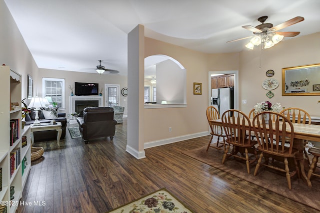 203 Abbey Ln, Wilmington, NC 28411 - dining area featuring ceiling fan, dark wood-type flooring, a fireplace, arched walkways, and baseboards