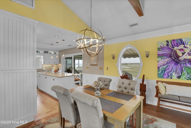 53 N Ridge Ln, Surf City, NC 28445 - dining space with a chandelier, a wainscoted wall, wood finished floors, and vaulted ceiling