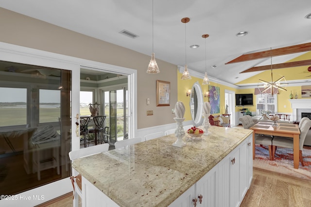 53 N Ridge Ln, Surf City, NC 28445 - kitchen with light stone counters, light wood-style floors, white cabinetry, a wainscoted wall, and a chandelier