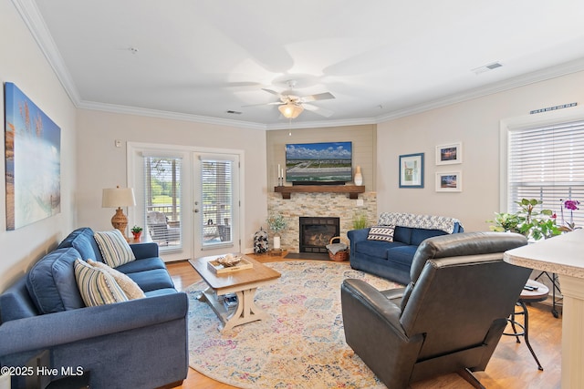 living room with crown molding, light wood finished floors, a ceiling fan, and a fireplace