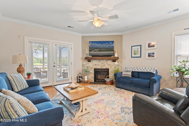 living area with ornamental molding, wood finished floors, ceiling fan, and a fireplace