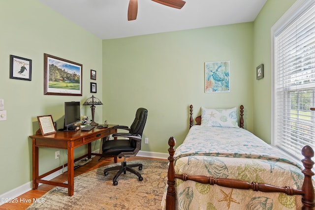 bedroom featuring baseboards, wood finished floors, an office area, and a ceiling fan