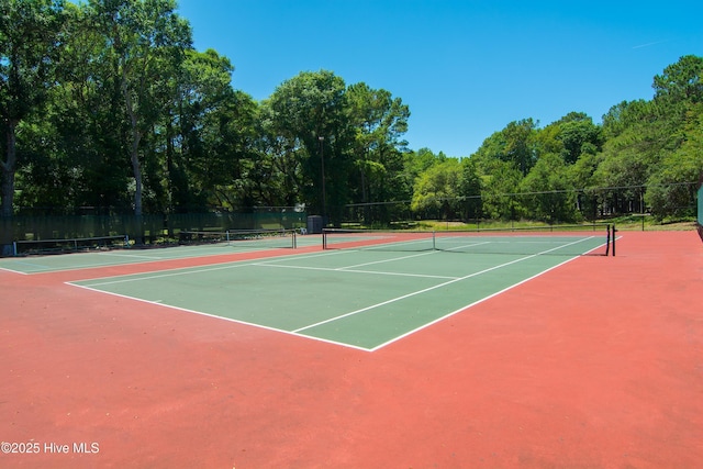 view of tennis court with fence, community basketball court, and a view of trees