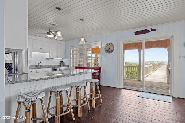 5709 Ocean Dr, Emerald Isle, NC 28594 - kitchen featuring a peninsula, white cabinets, tasteful backsplash, light stone countertops, and a breakfast bar area