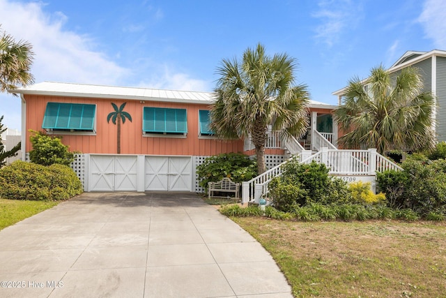 5709 Ocean Dr, Emerald Isle, NC 28594 - view of front facade featuring an attached garage, concrete driveway, stairway, and metal roof