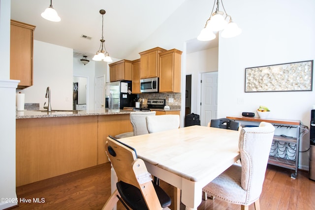 dining space featuring light wood-style flooring, a chandelier, and high vaulted ceiling