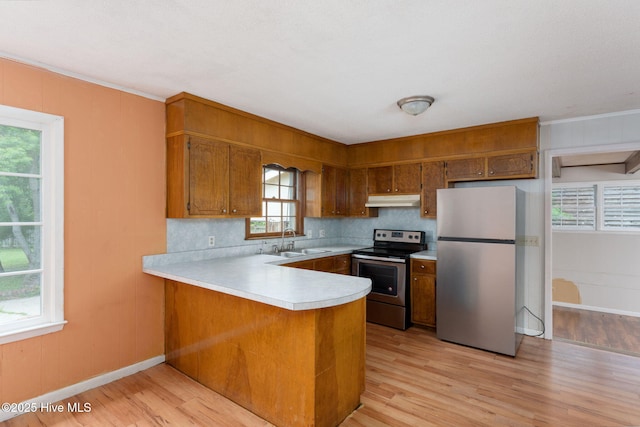 514 Mohican Trl, Wilmington, NC 28409 - kitchen with appliances with stainless steel finishes, under cabinet range hood, a sink, and brown cabinetry