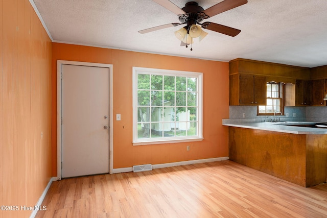 514 Mohican Trl, Wilmington, NC 28409 - kitchen with light wood finished floors, brown cabinets, plenty of natural light, light countertops, and a textured ceiling