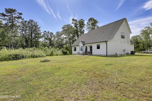 back of house featuring a yard, a patio, roof with shingles, and a fire pit