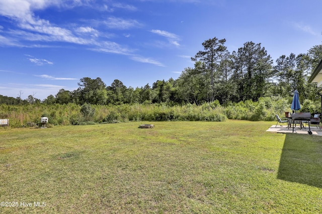 view of green lawn with a patio area and an outdoor fire pit
