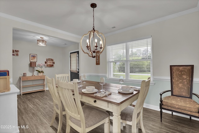 dining space with wood finished floors, a chandelier, crown molding, and baseboards