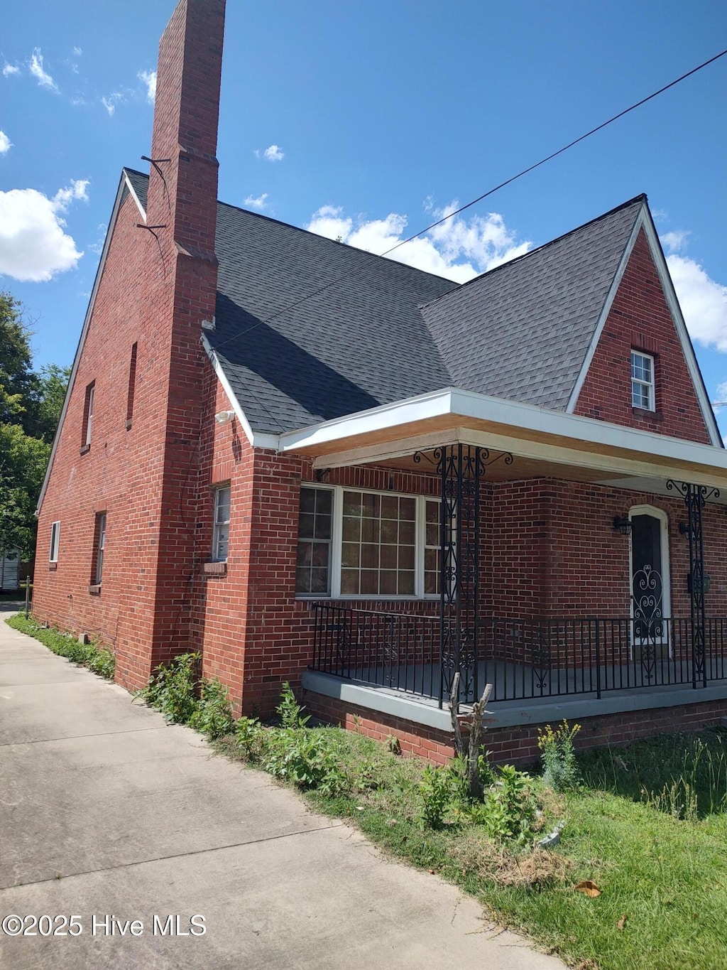 403 S William St, Goldsboro, NC 27530 - view of side of property with a chimney, covered porch, roof with shingles, and brick siding
