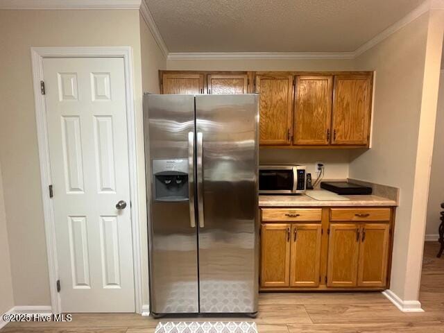 115 Oak Hills Dr, Rocky Point, NC 28457 - kitchen featuring stainless steel appliances, ornamental molding, brown cabinetry, light countertops, and light wood finished floors