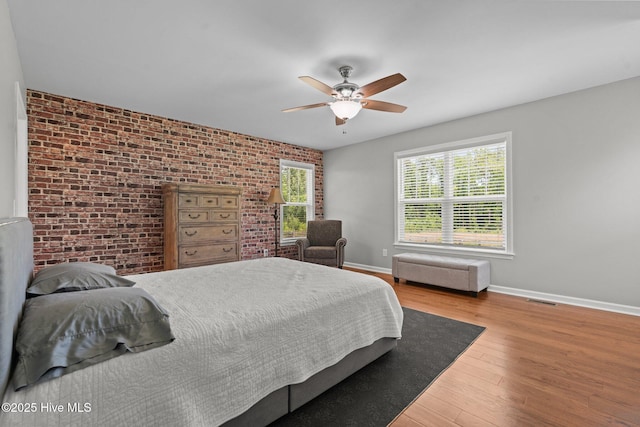 1139 Cranes Creek Rd, Cameron, NC 28326 - bedroom with brick wall, baseboards, wood finished floors, and a ceiling fan