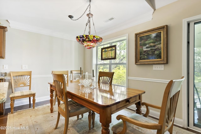 dining room featuring ornamental molding, baseboards, and light wood finished floors