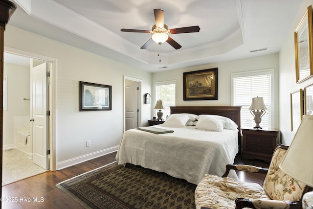 bedroom featuring a raised ceiling, dark wood finished floors, baseboards, crown molding, and a ceiling fan