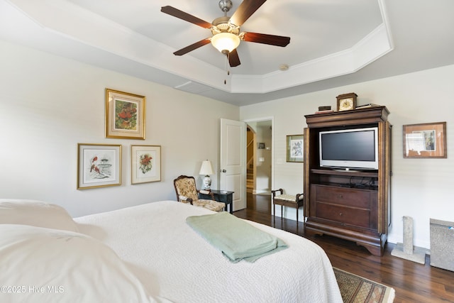 bedroom featuring dark wood-style flooring, a raised ceiling, and a ceiling fan