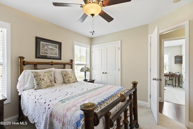 bedroom with light colored carpet, a closet, baseboards, and a ceiling fan