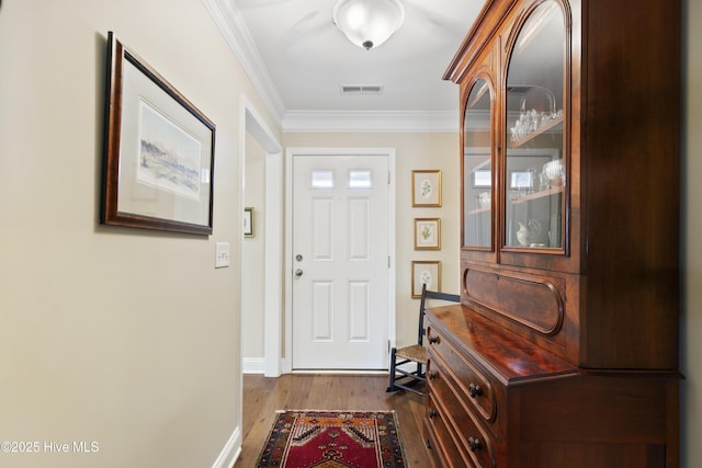 entrance foyer featuring wood finished floors, crown molding, and baseboards